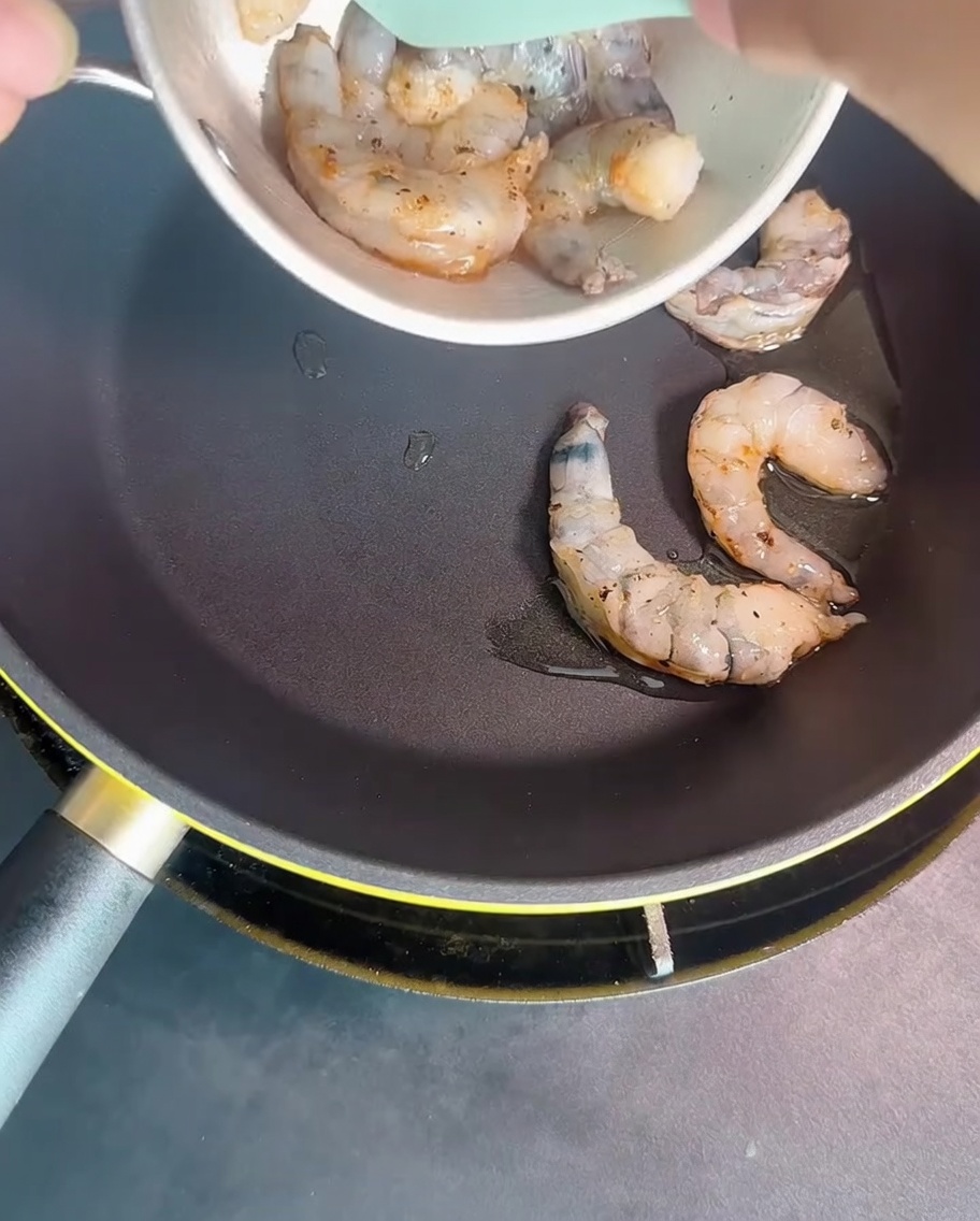 달궈진 팬에서 새우가 불투명하게 익어가는 모습.