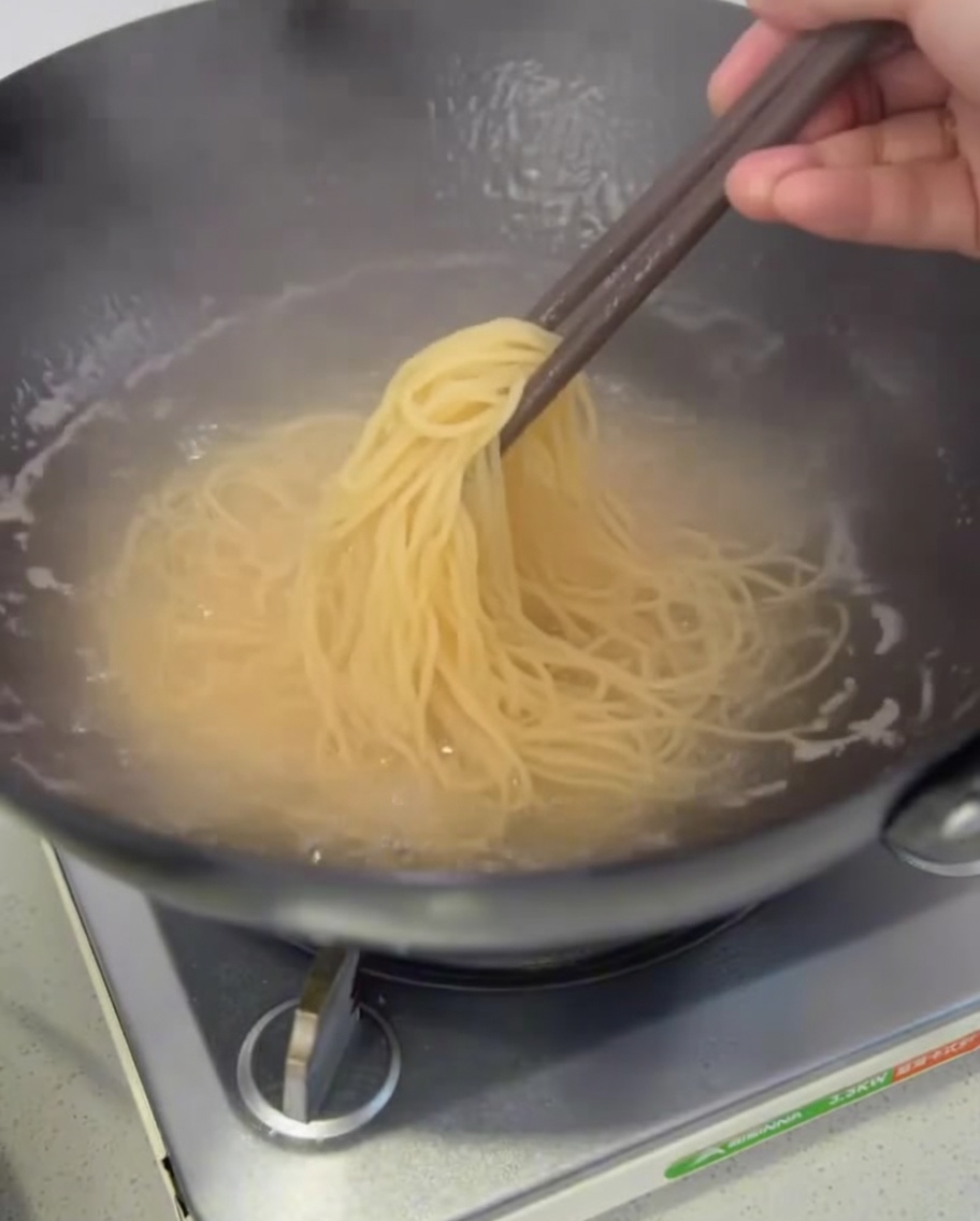 삶아진 스파게티 면을 냄비에서 건져 물기를 빼는 모습.