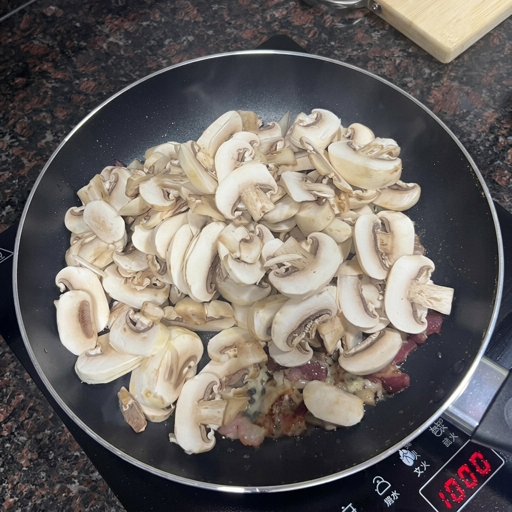 베이컨과 마늘이 있는 팬에 슬라이스한 양송이버섯을 넣는 모습.