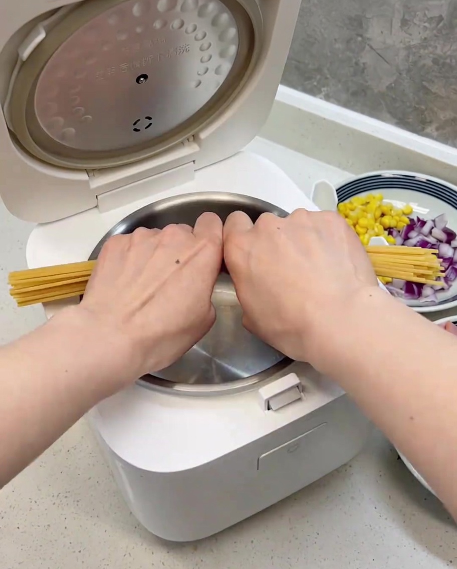 반으로 부러뜨려 깨끗한 전기밥솥 내솥에 가지런히 담긴 스파게티 면.