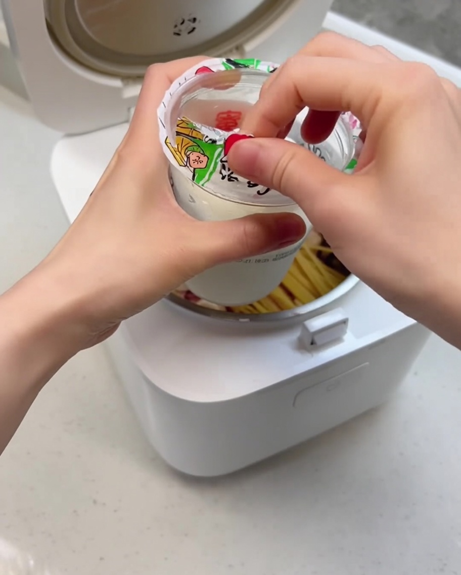 전기밥솥 안의 재료 위로 크리미한 아이스크림을 붓는 근접 촬영 사진.