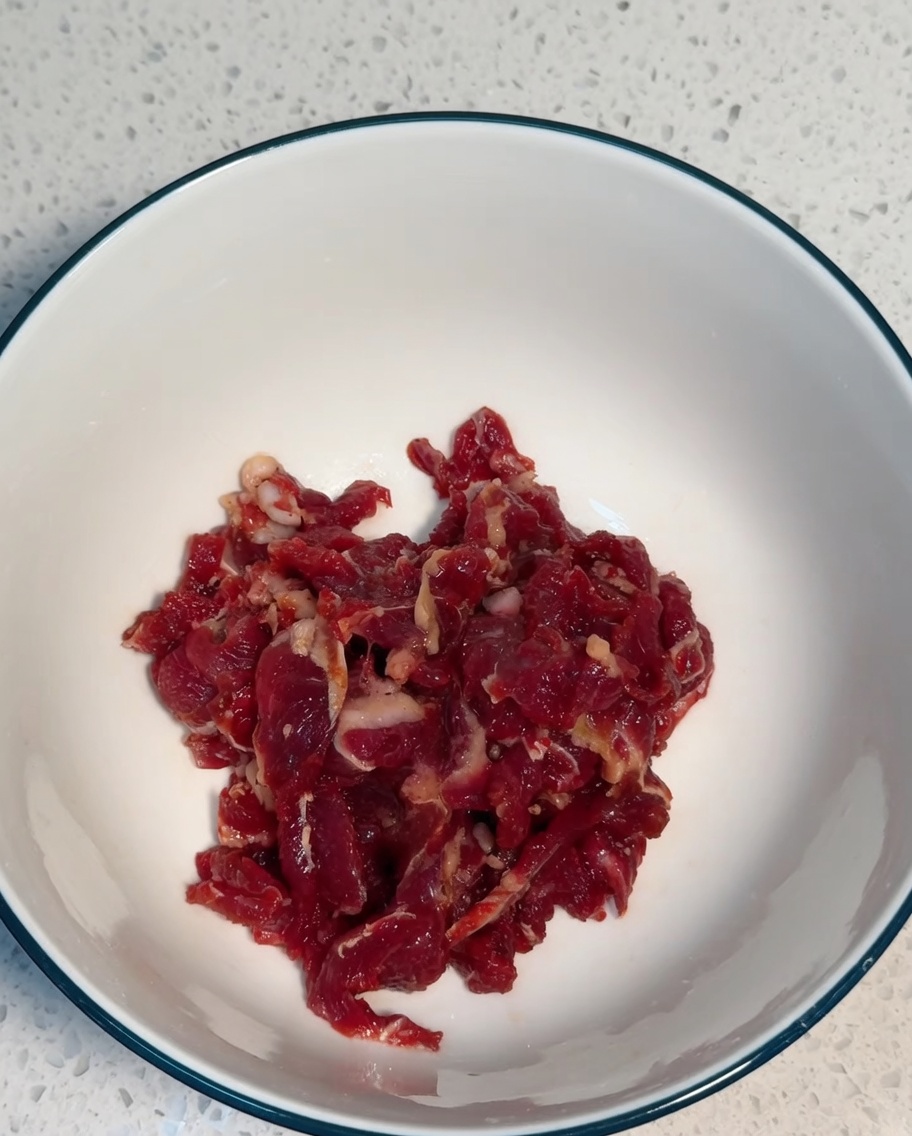 흰 볼에 얇게 썬 소고기와 밑간 재료를 넣어 잘 버무리는 모습.