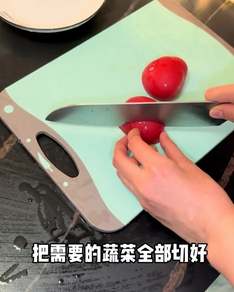 초록색 도마 위에서 식칼로 신선한 붉은 토마토를 썰고 있는 모습.