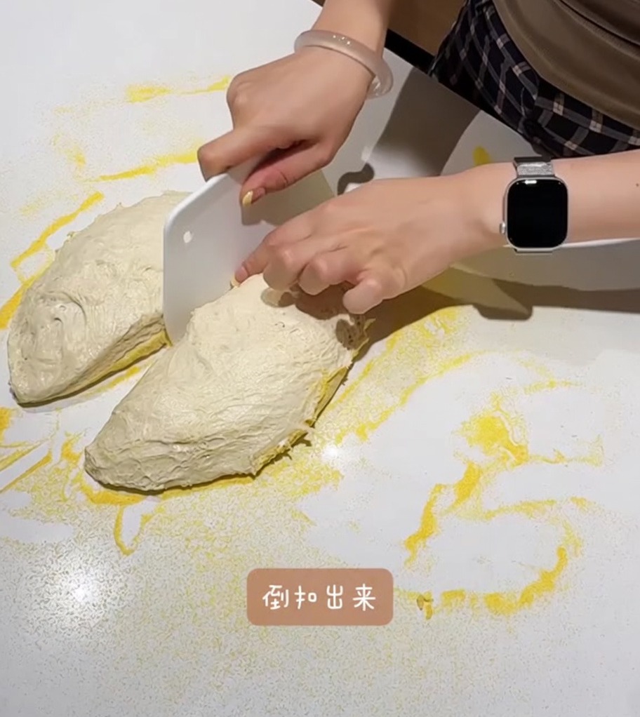 옥수수 가루가 뿌려진 작업대에서 반죽을 두 덩이로 나누고 있습니다.