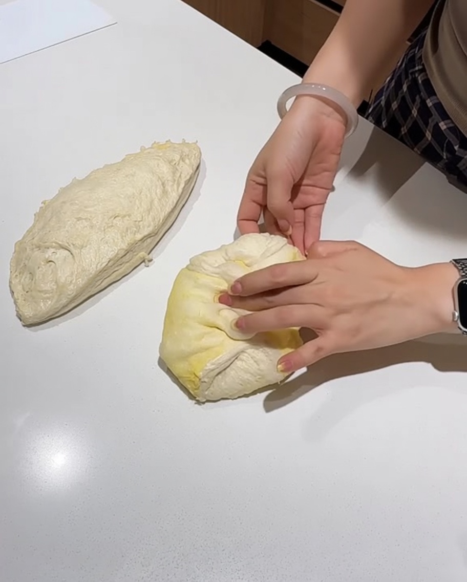 작업대 위에서 반죽을 팽팽한 공 모양으로 성형하고 있습니다.