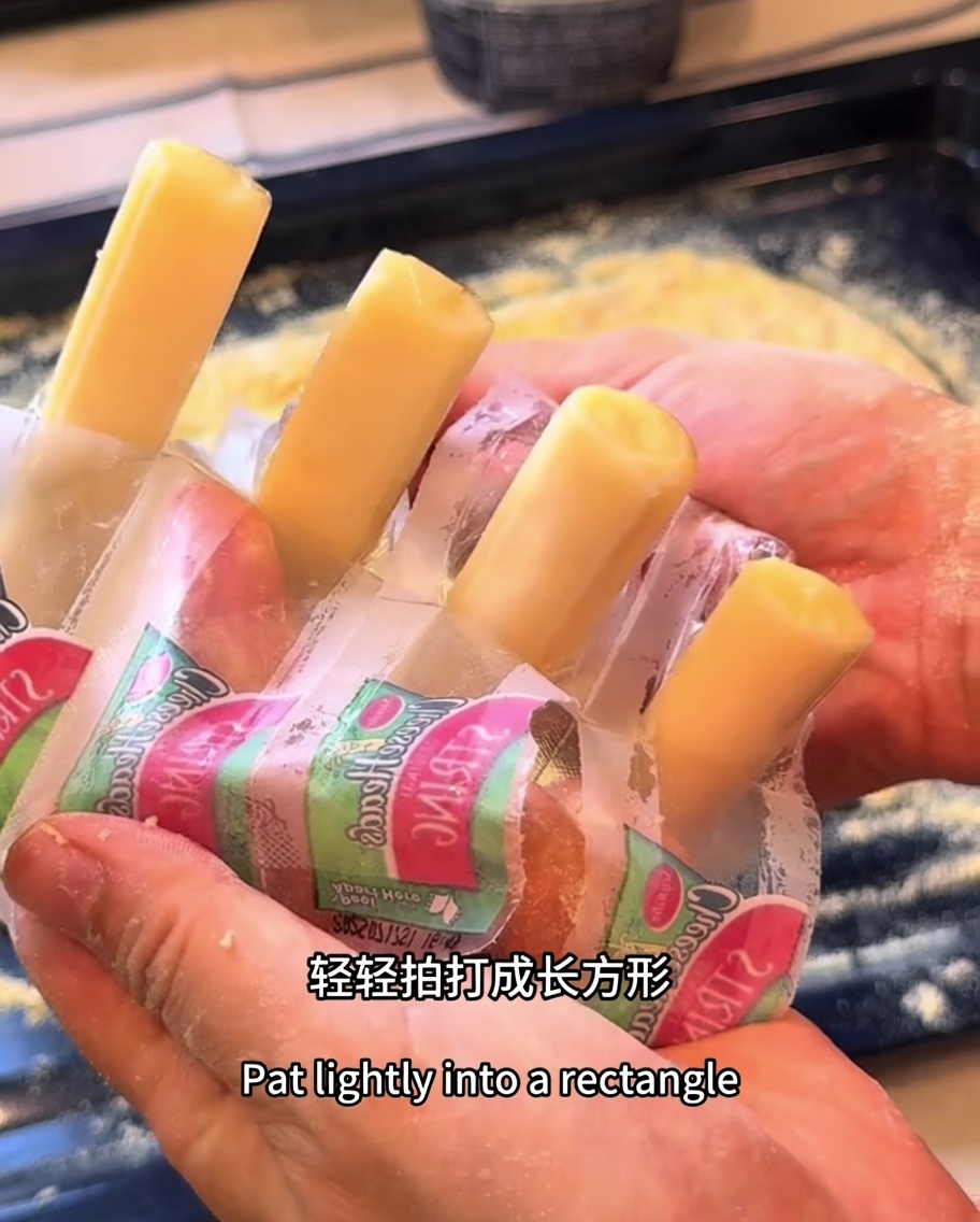 직사각형 피자 도우의 가장자리를 따라 모차렐라 치즈 스틱을 배치한 모습.