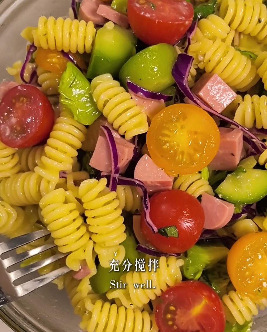 볼 안에서 올리브 오일과 함께 파스타와 샐러드 재료를 버무리는 모습.