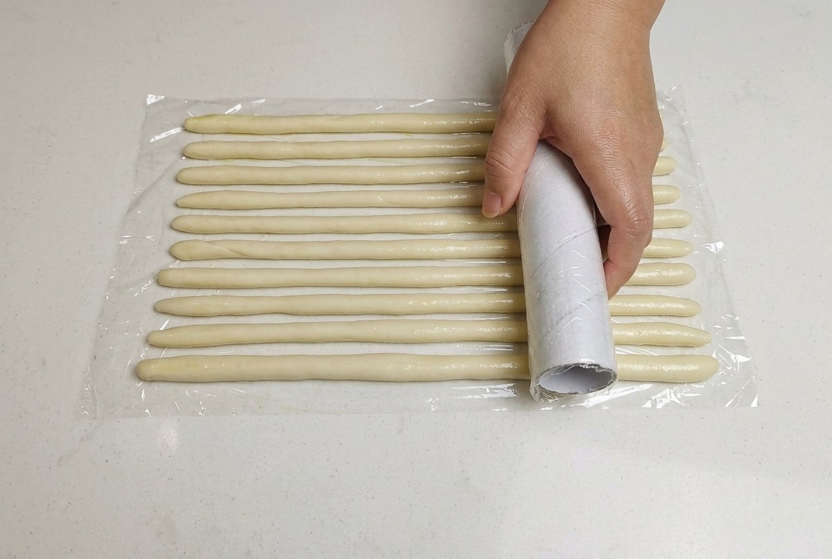 줄 모양으로 배열된 반죽 위에 랩을 씌우는 모습.