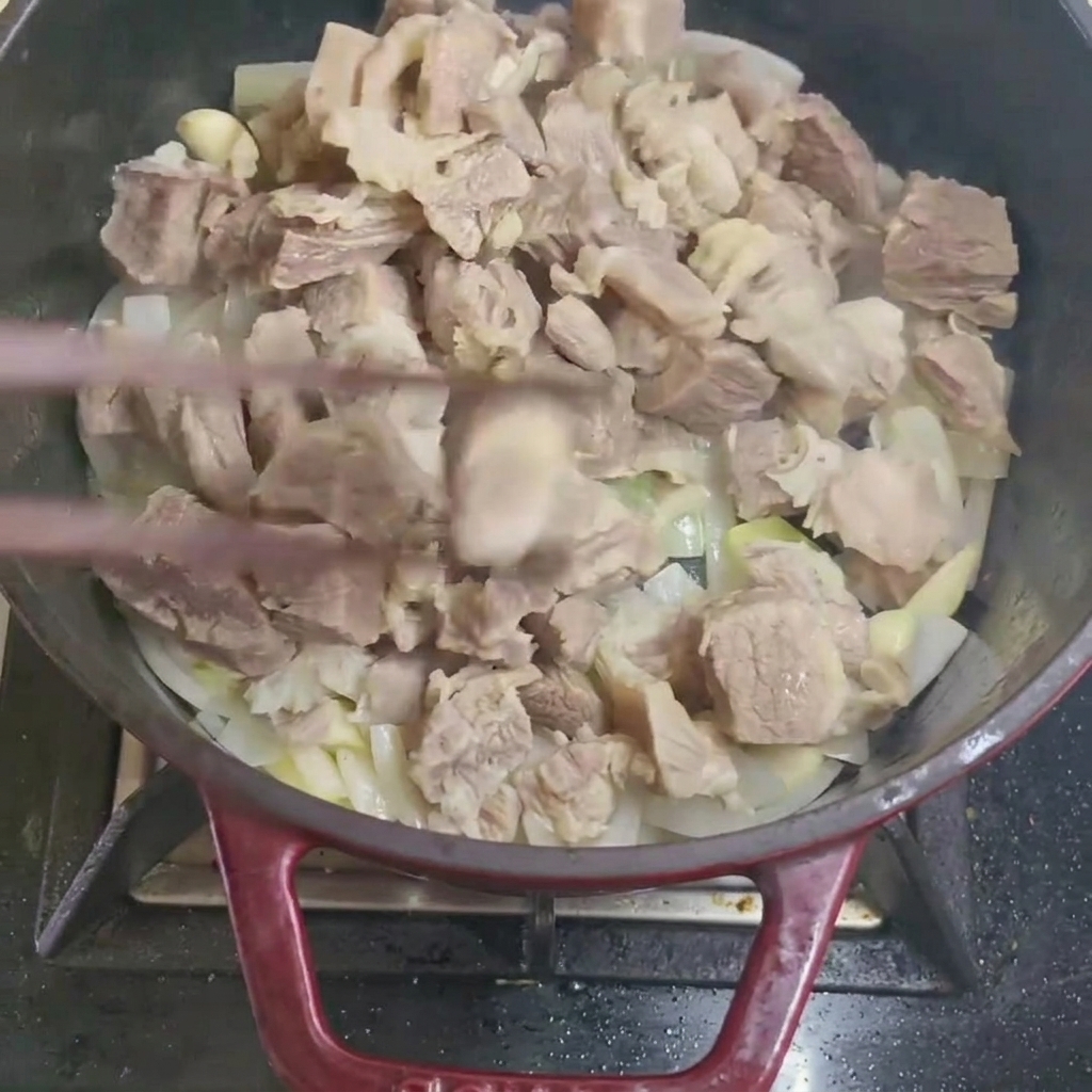 데친 소고기 조각을 양파, 마늘과 함께 냄비에서 볶는 모습