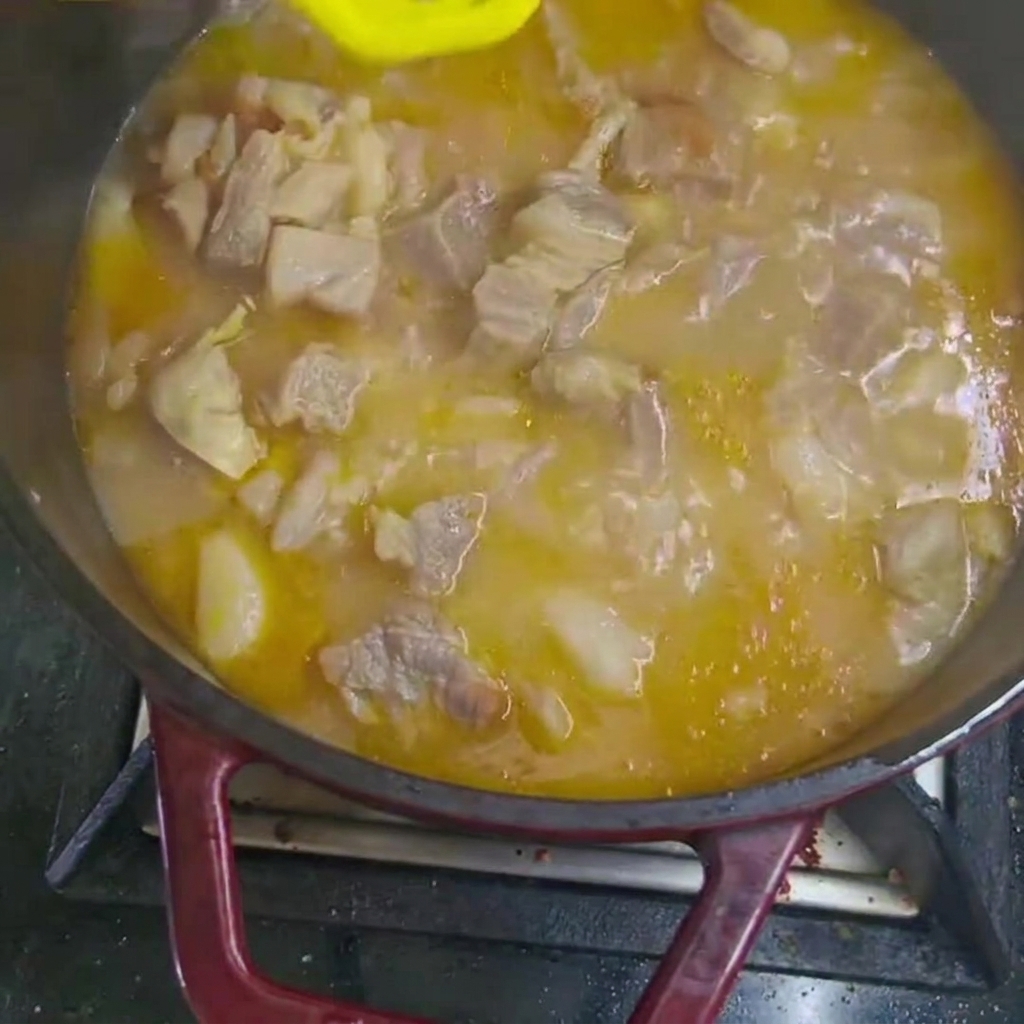 끓고 있는 스튜에 당근과 감자 조각을 넣는 모습