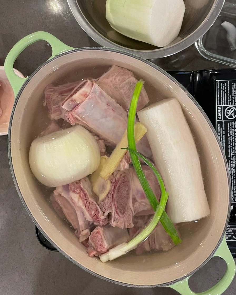 갈비, 채소, 향신채가 완전히 잠기도록 냄비에 물을 붓는 모습.