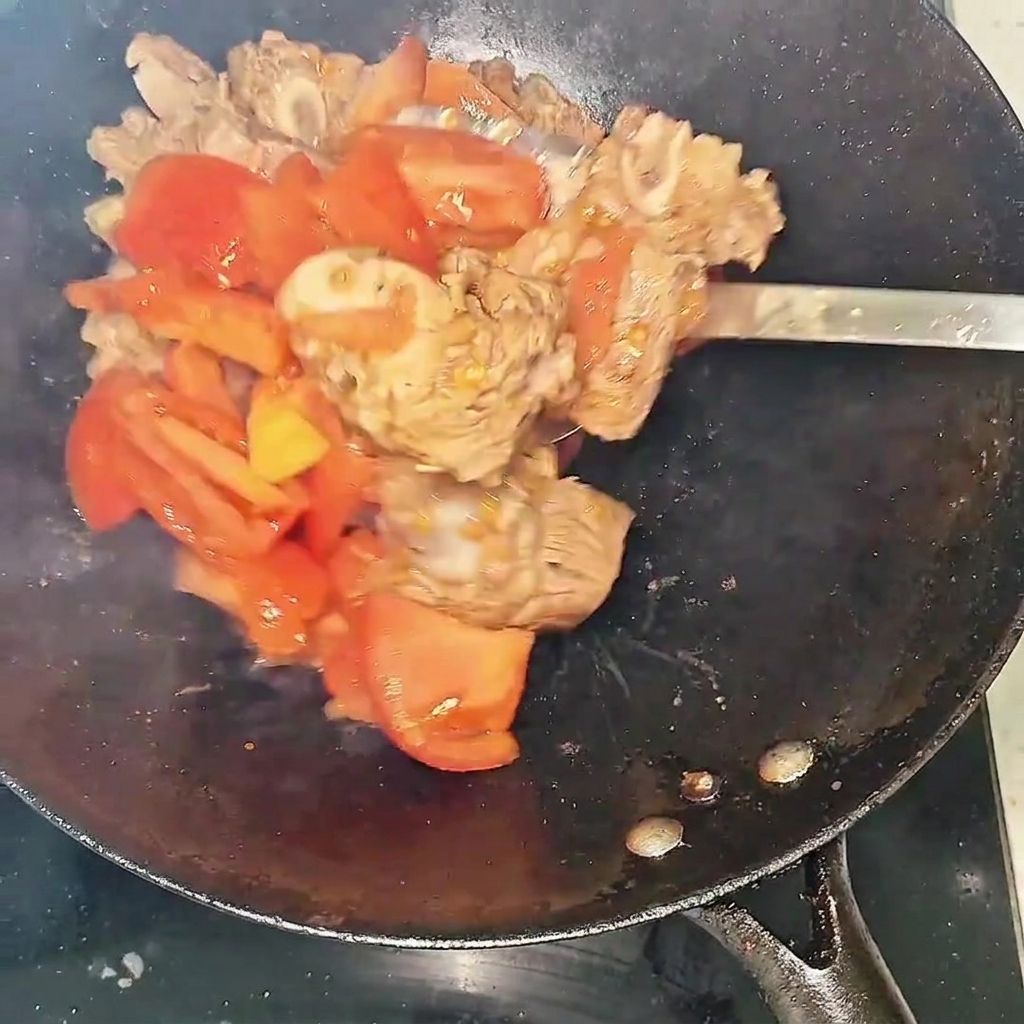 소갈비와 토마토가 웍에서 볶아지며 붉은 즙이 나오는 모습.