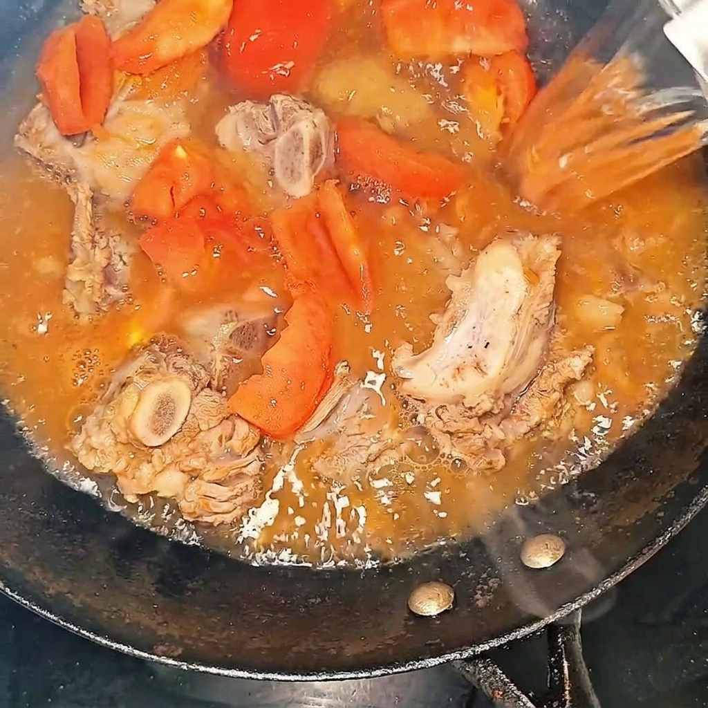 웍에 담긴 재료 위로 뜨거운 물을 붓는 모습.