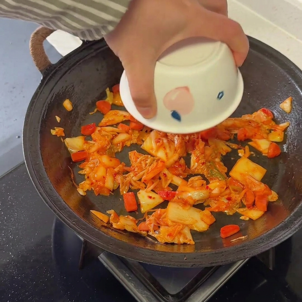 김치와 소시지 볶음에 찬밥을 넣고 섞는 모습.