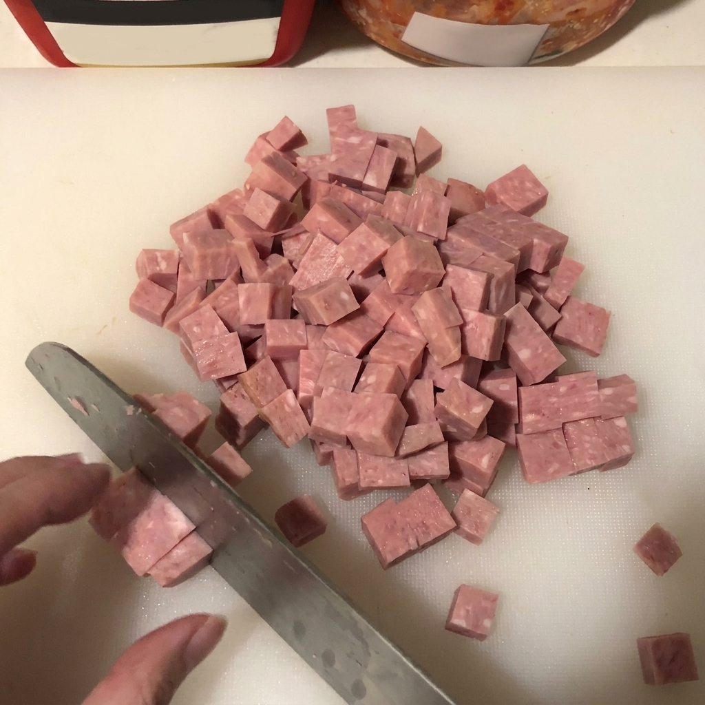 도마 위에서 스팸을 일정한 크기로 깍둑썰기하는 모습.