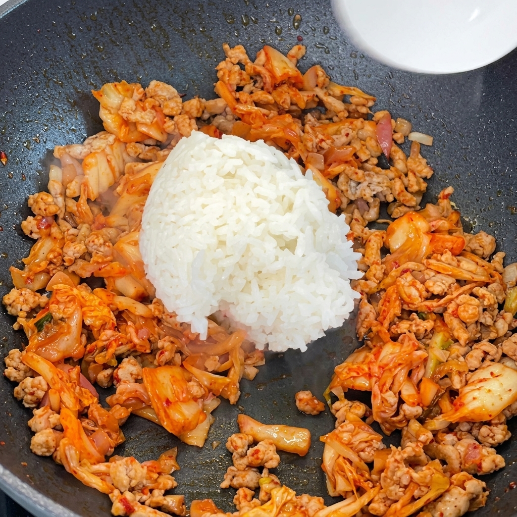 볶은 김치와 돼지고기에 밥을 넣는 모습.