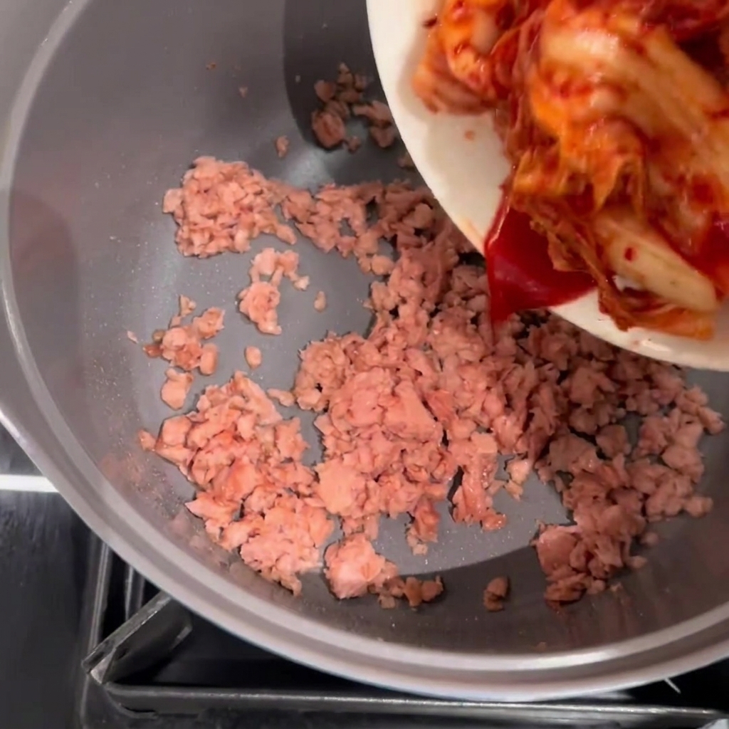 노릇하게 볶은 스팸에 김치를 넣는 모습.