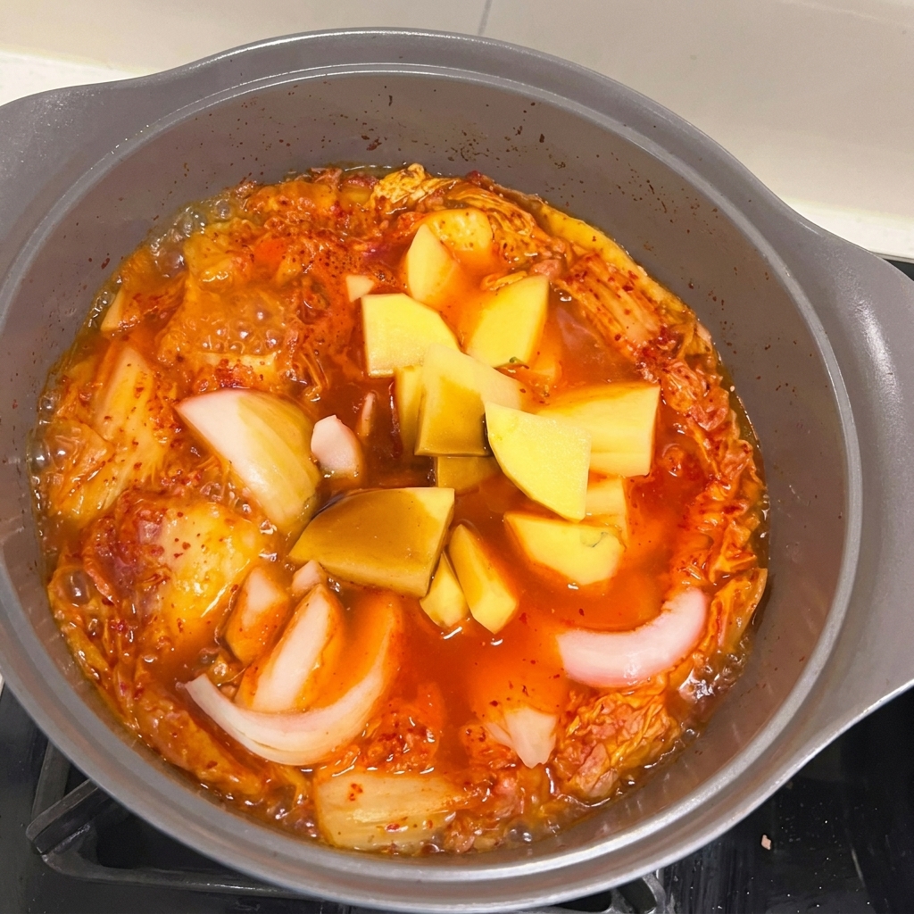 찌개에 썬 양파와 감자를 넣는 모습.