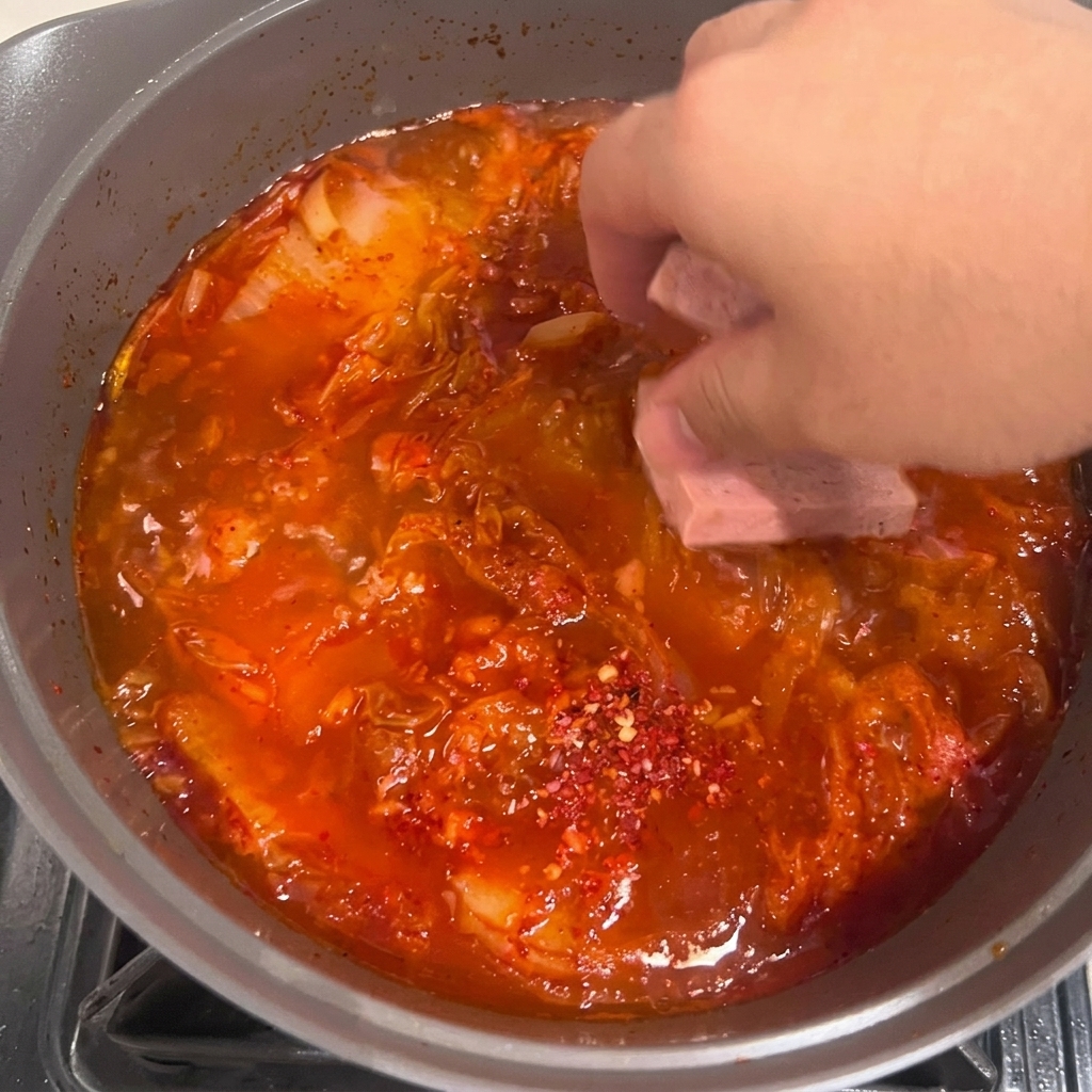 보글보글 끓는 김치찌개에 두부를 넣는 모습.