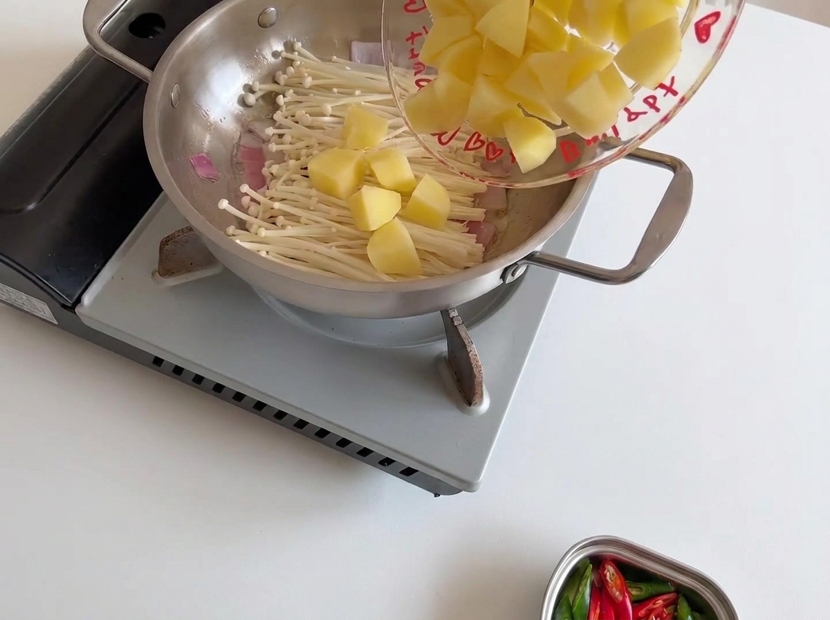 팽이버섯 위에 썰어둔 감자를 올리는 모습.