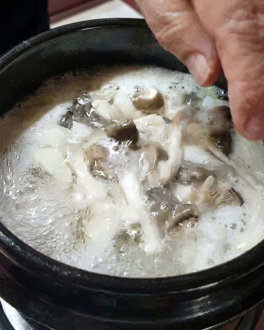 채 썬 양파와 버섯을 찌개에 넣는 모습.