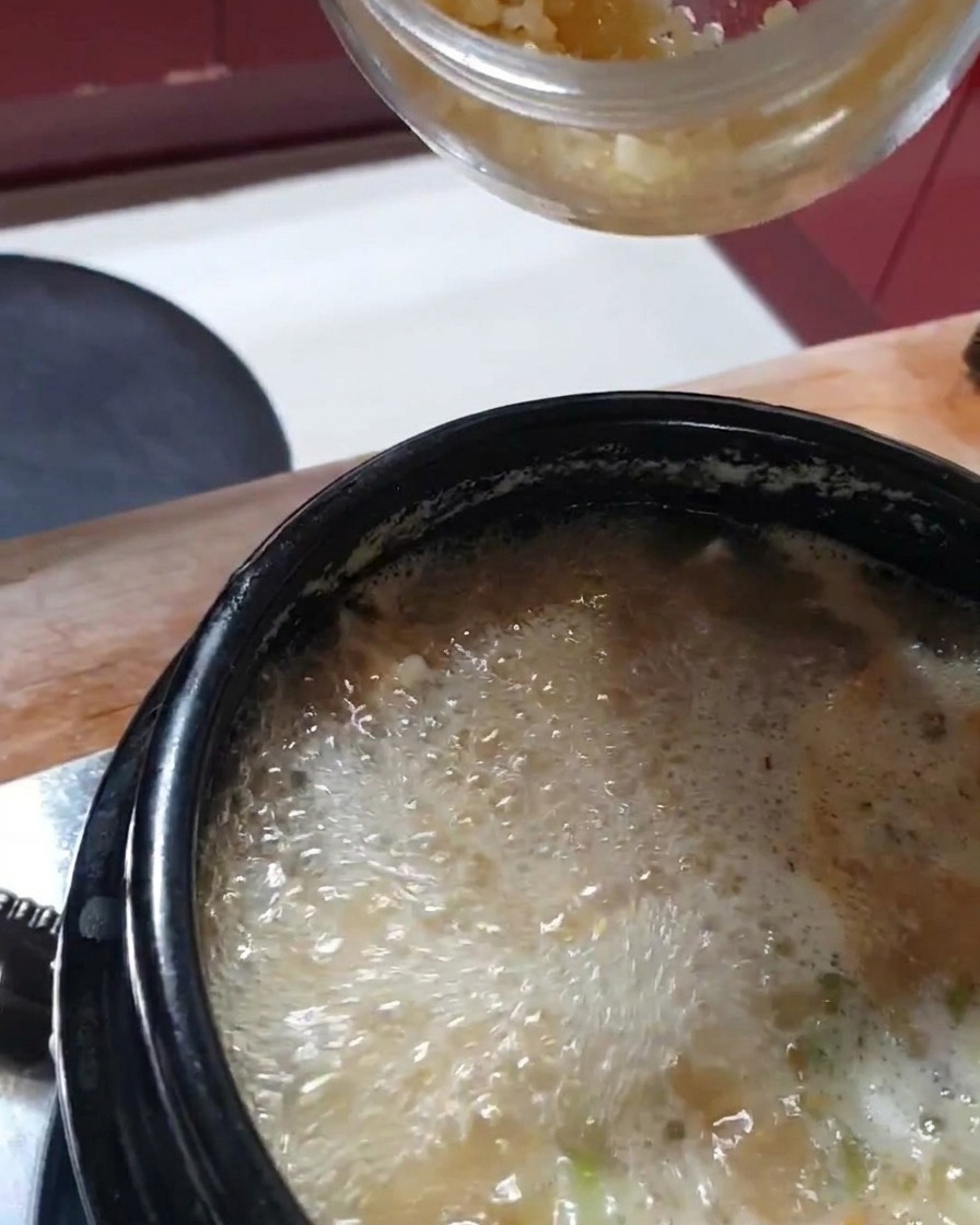 보글보글 끓는 찌개에 다진 마늘을 넣는 모습.