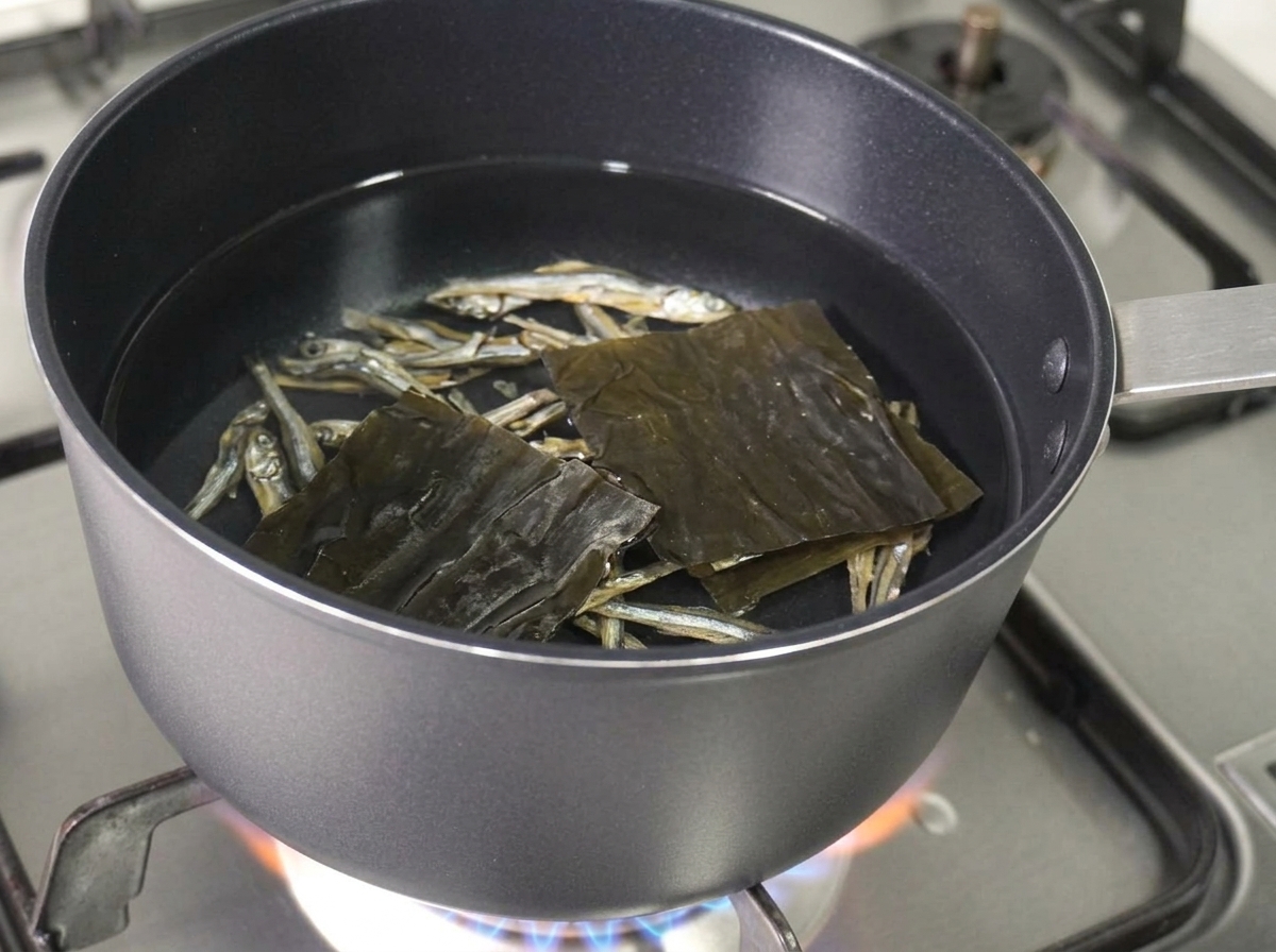 냄비 속 물에 멸치, 다시마, 버섯 기둥을 넣는 모습.