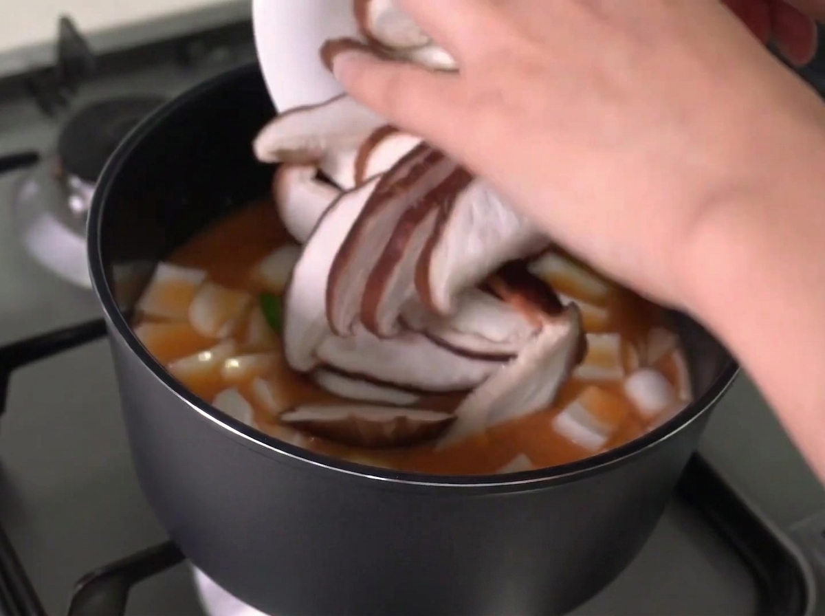 찌개에 슬라이스한 표고버섯을 넣는 모습.