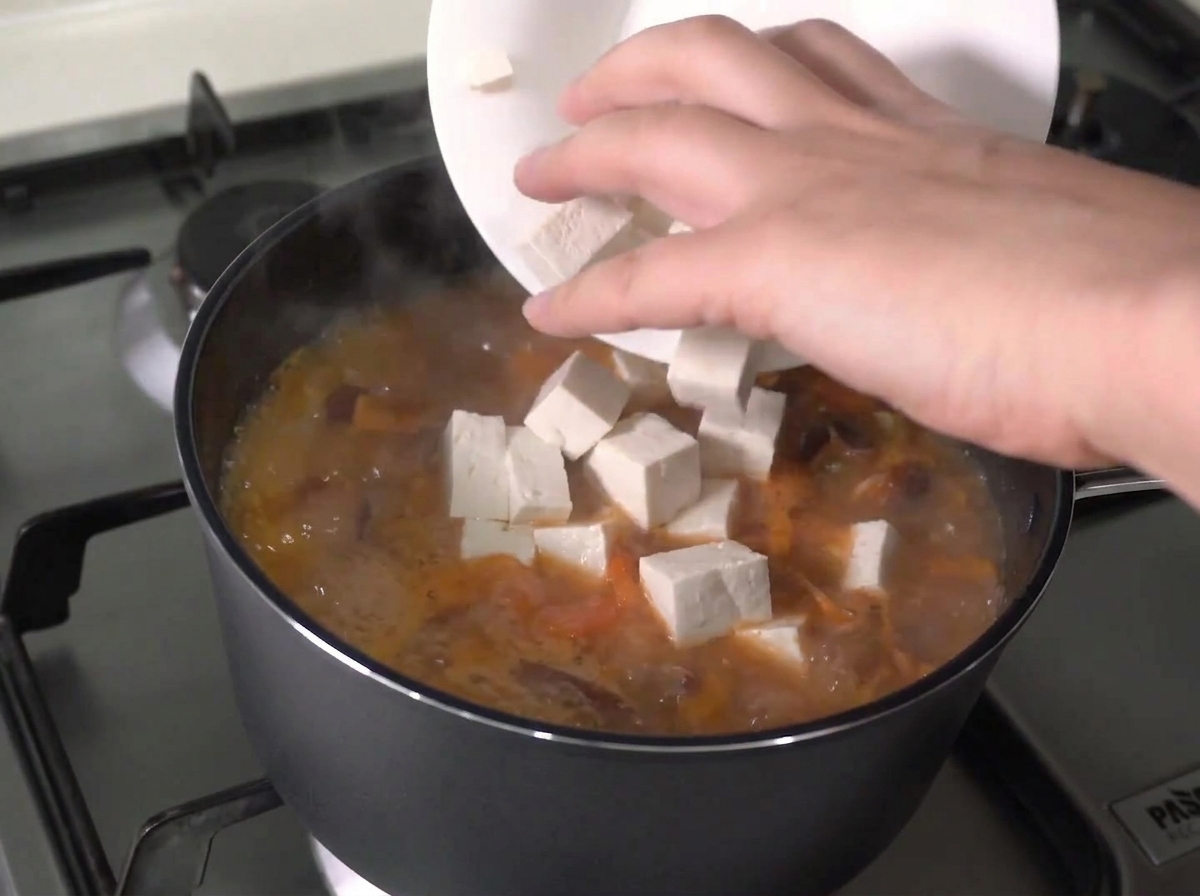 팔팔 끓는 찌개에 두부를 넣는 모습.