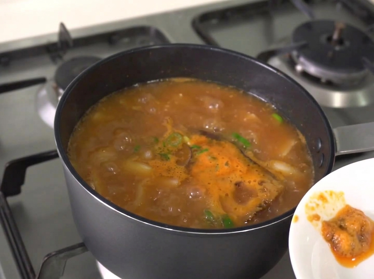 찌개 위로 떠오르는 거품을 숟가락으로 걷어내는 모습.