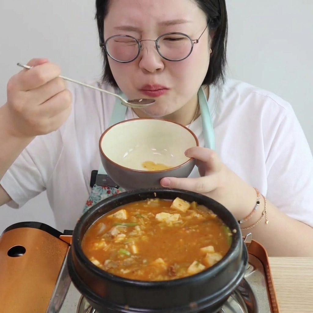 물을 붓고 끓기 시작하는 뚝배기에 채소를 넣는 모습.