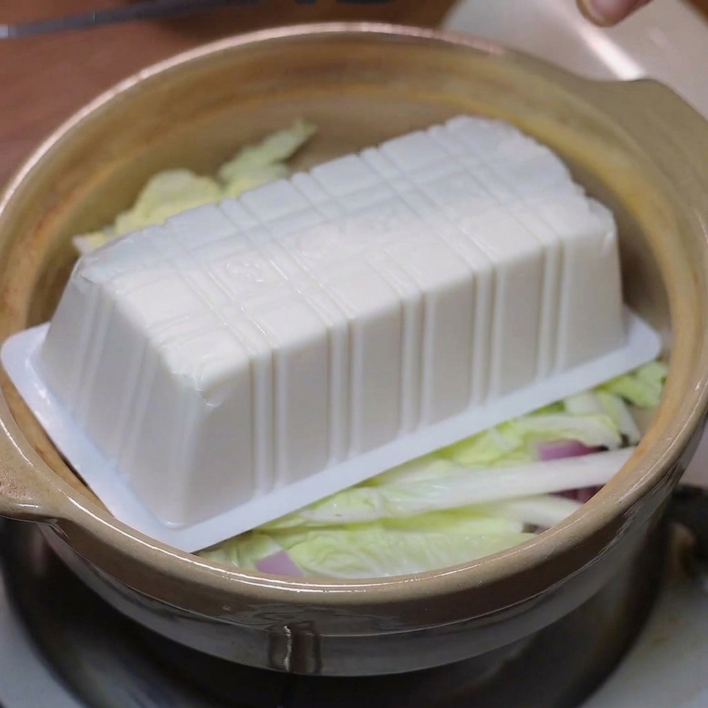 배추와 양파 위에 순두부를 조심스럽게 얹는 모습.