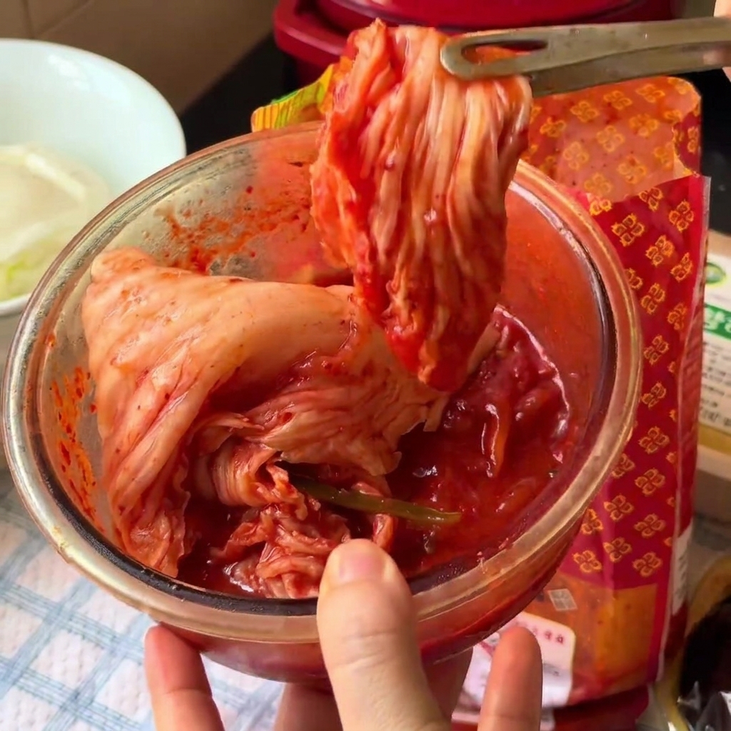 유리 볼 안에서 주방 가위로 김치를 먹기 좋은 크기로 자르는 모습.
