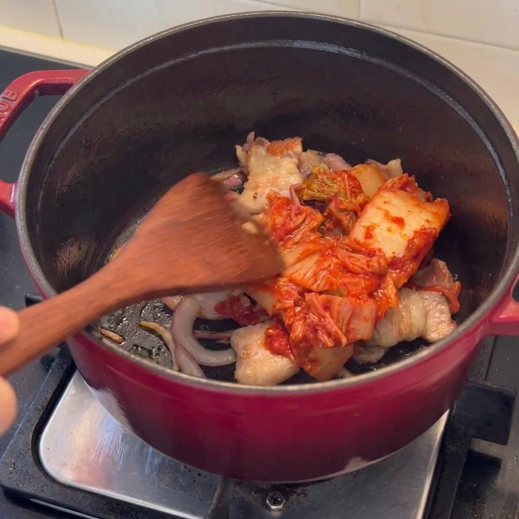 볶은 삼겹살에 김치를 넣고 함께 볶는 모습.