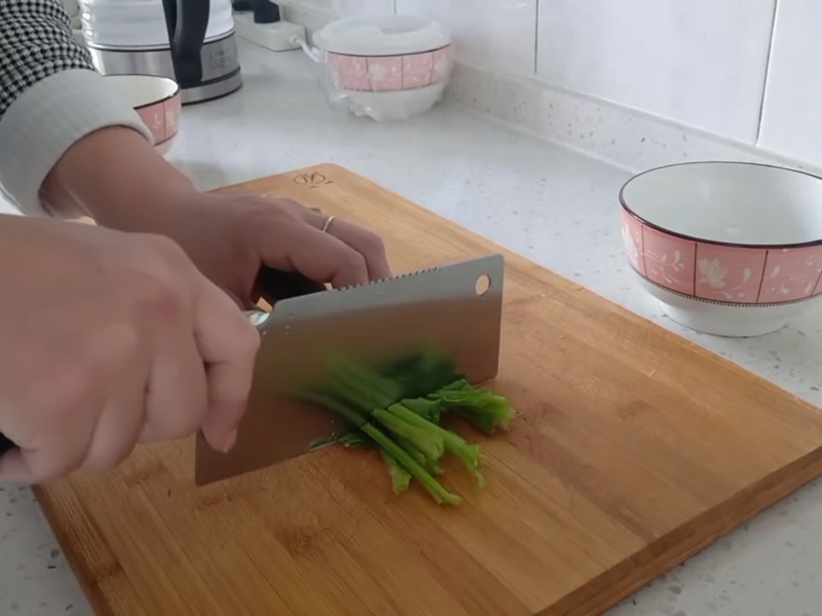 도마 위에서 신선한 시금치를 먹기 좋은 크기로 써는 모습.