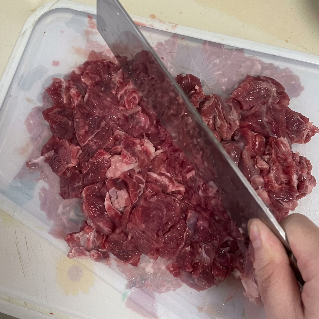 도마 위에서 고기용 칼로 신선한 소고기를 곱게 다지는 모습.
