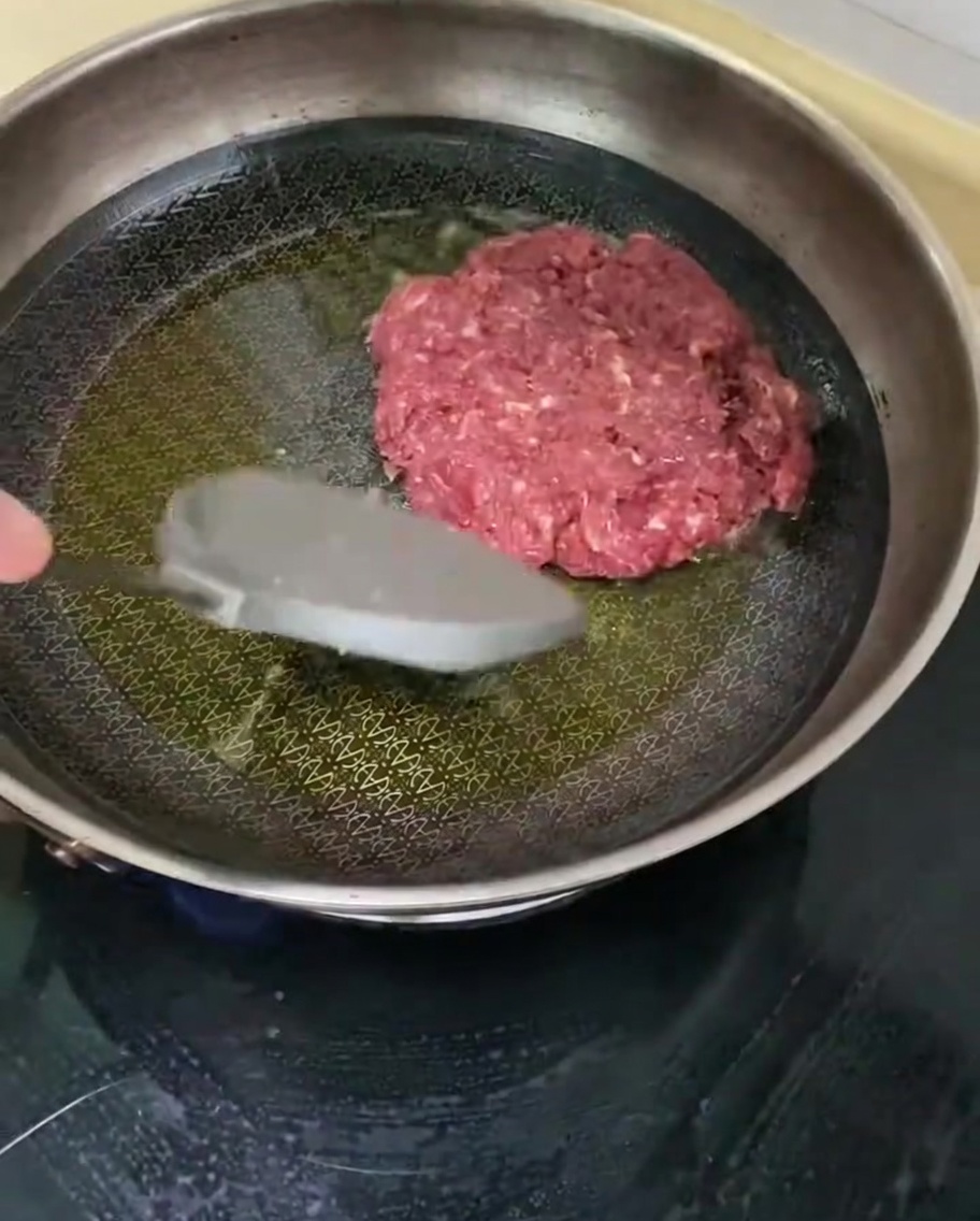 뜨거운 팬 위에서 소고기 패티가 맛있게 익어가는 모습.