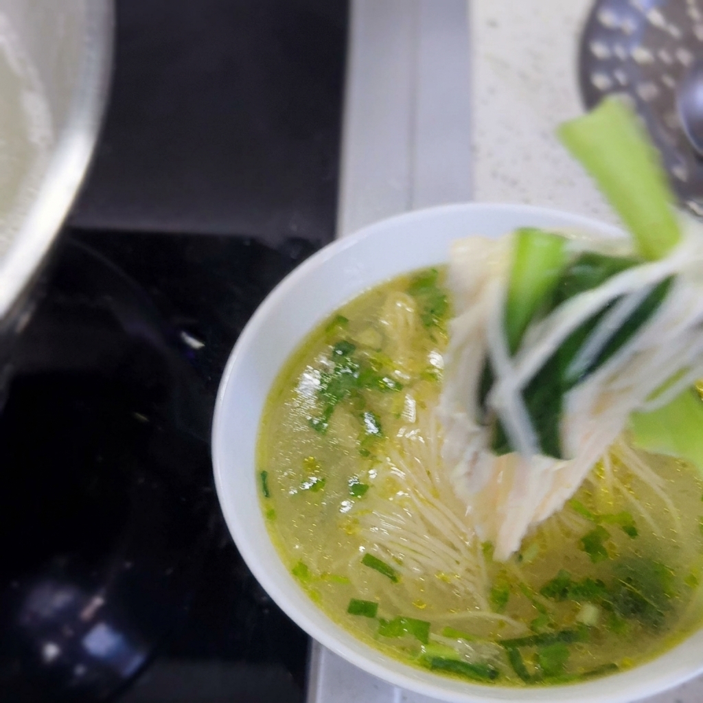 따뜻한 면, 채소, 닭고기가 올라간 먹음직스러운 완성 요리.