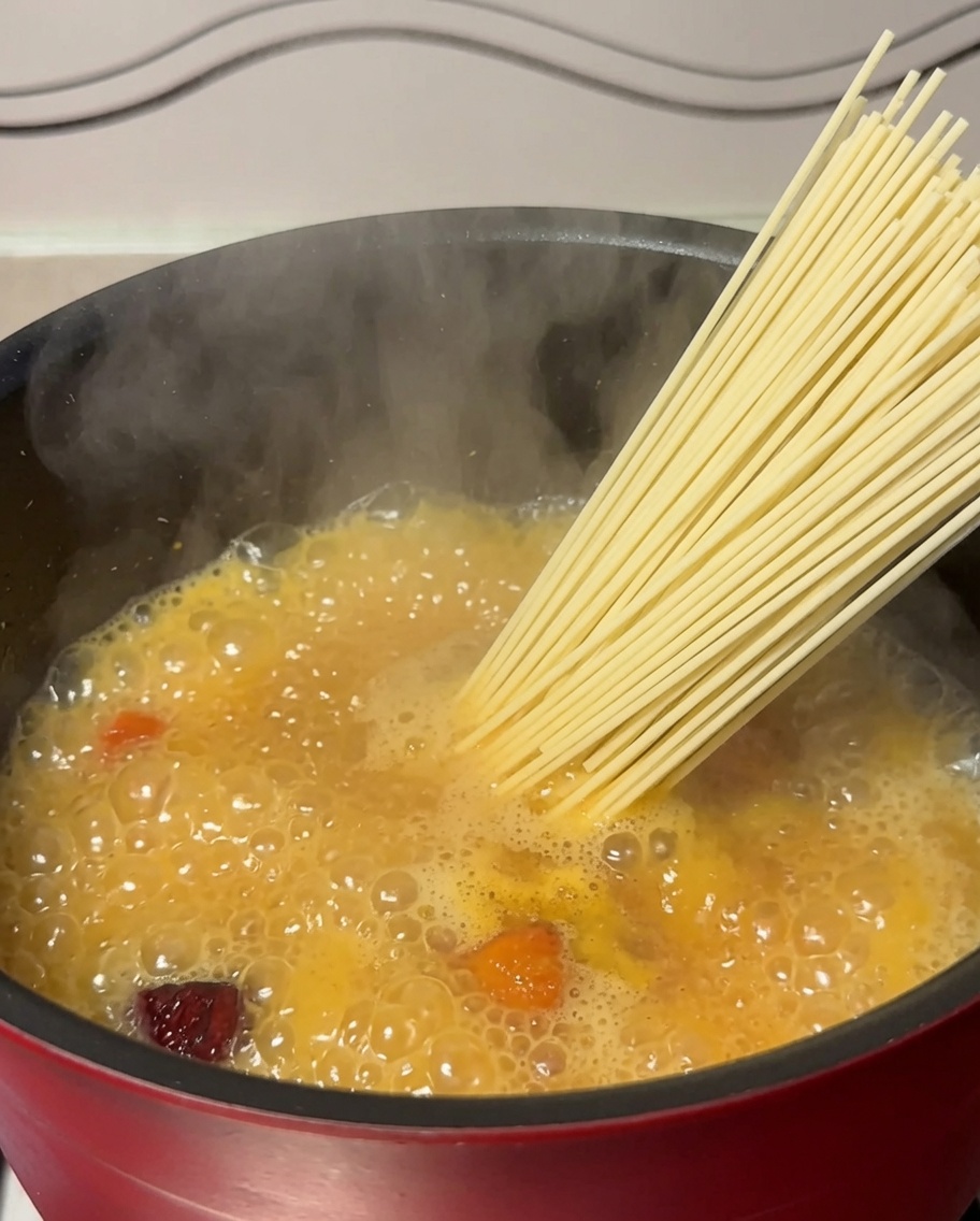 끓는 닭고기 수프가 담긴 냄비에 건면을 넣는 모습.