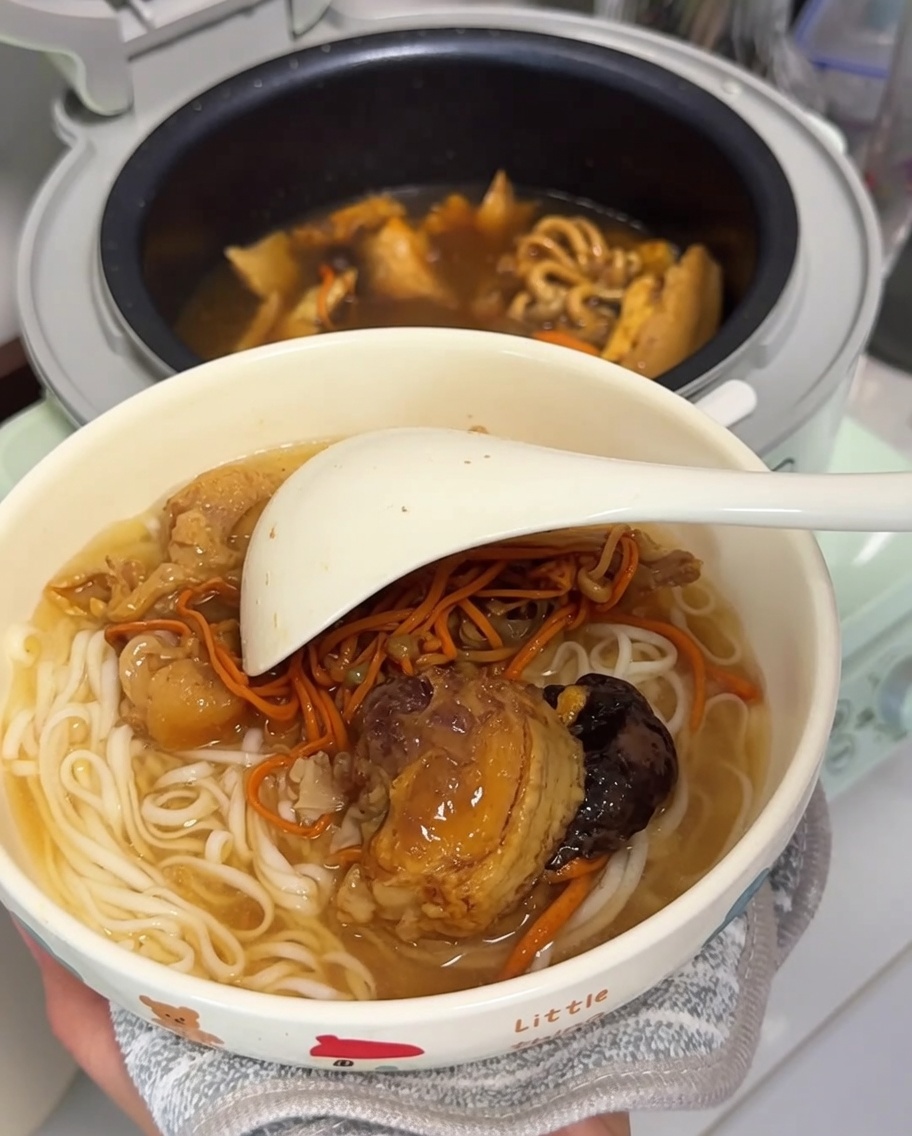 하얀 국수와 닭고기, 건버섯이 담긴 그릇 안에 큰 하얀 국자가 놓여 있어 서빙할 준비가 된 모습.