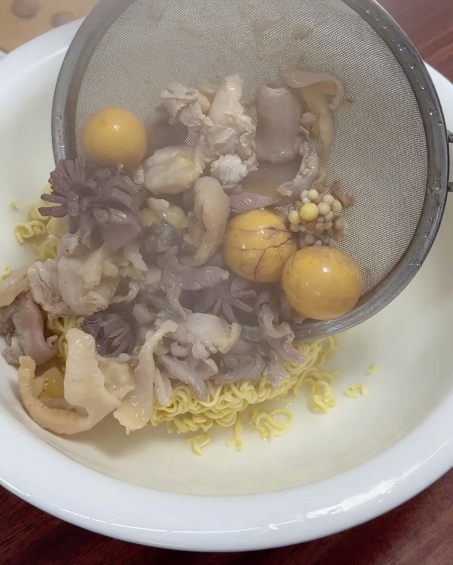 익은 고기와 노른자를 망으로 건져 면 위에 담는 모습.