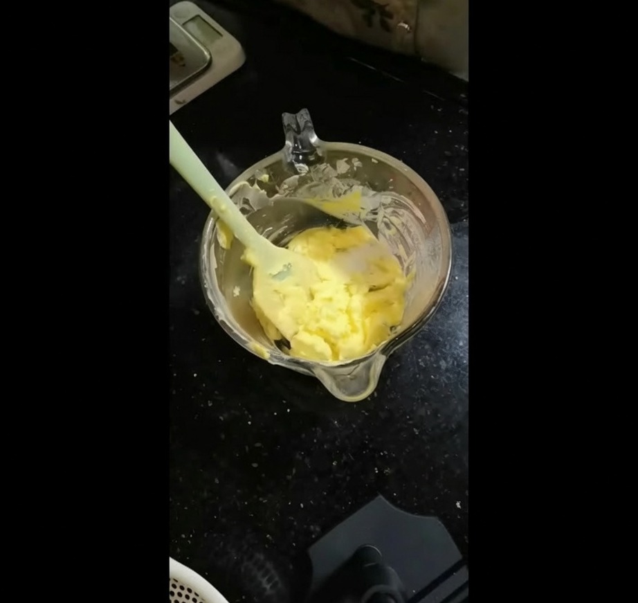 부드러운 노란 버터가 담긴 볼에 다진 녹색 허브 믹스를 넣는 모습.