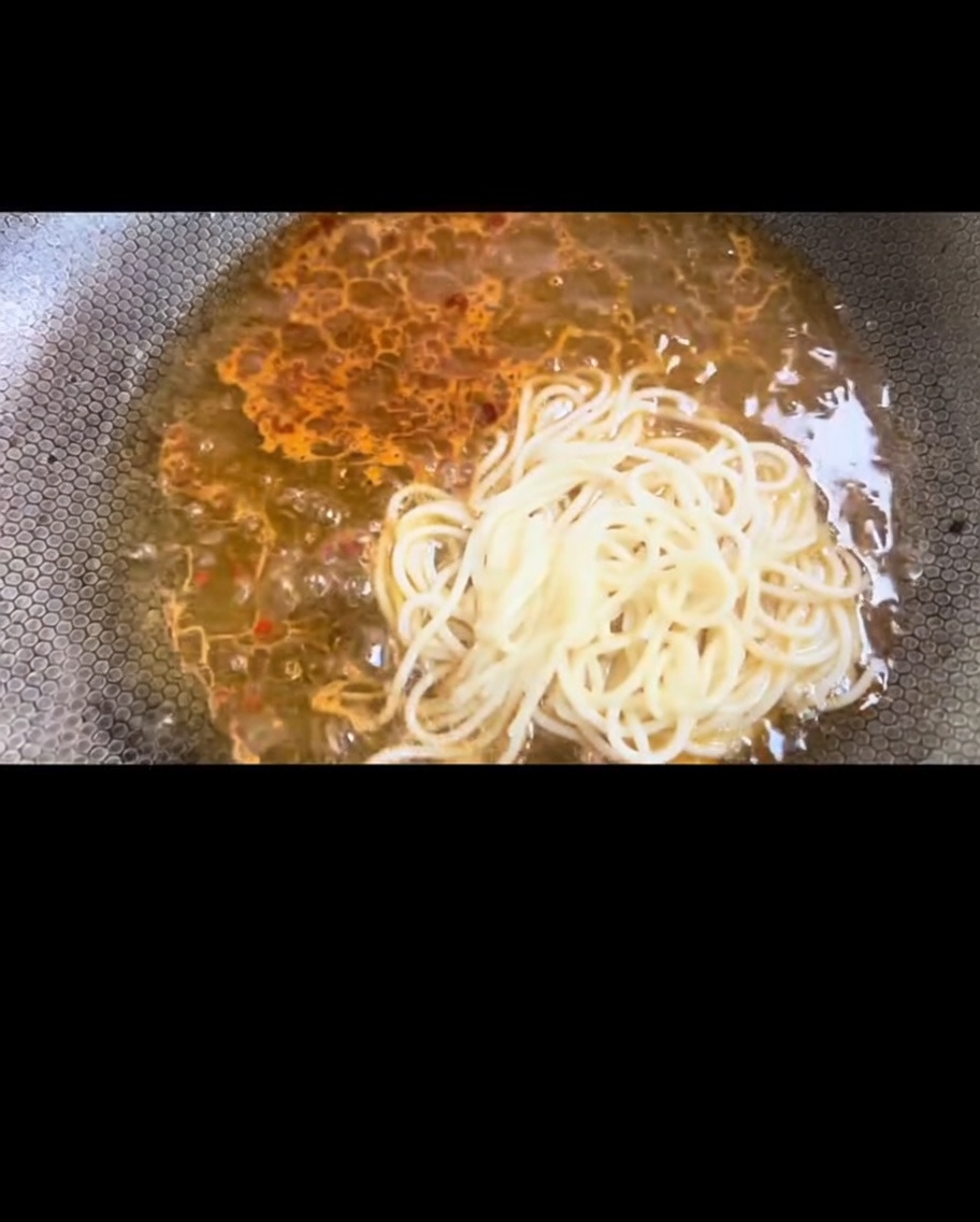 삶은 스파게티 면을 웍에 넣어 소스와 섞는 모습.