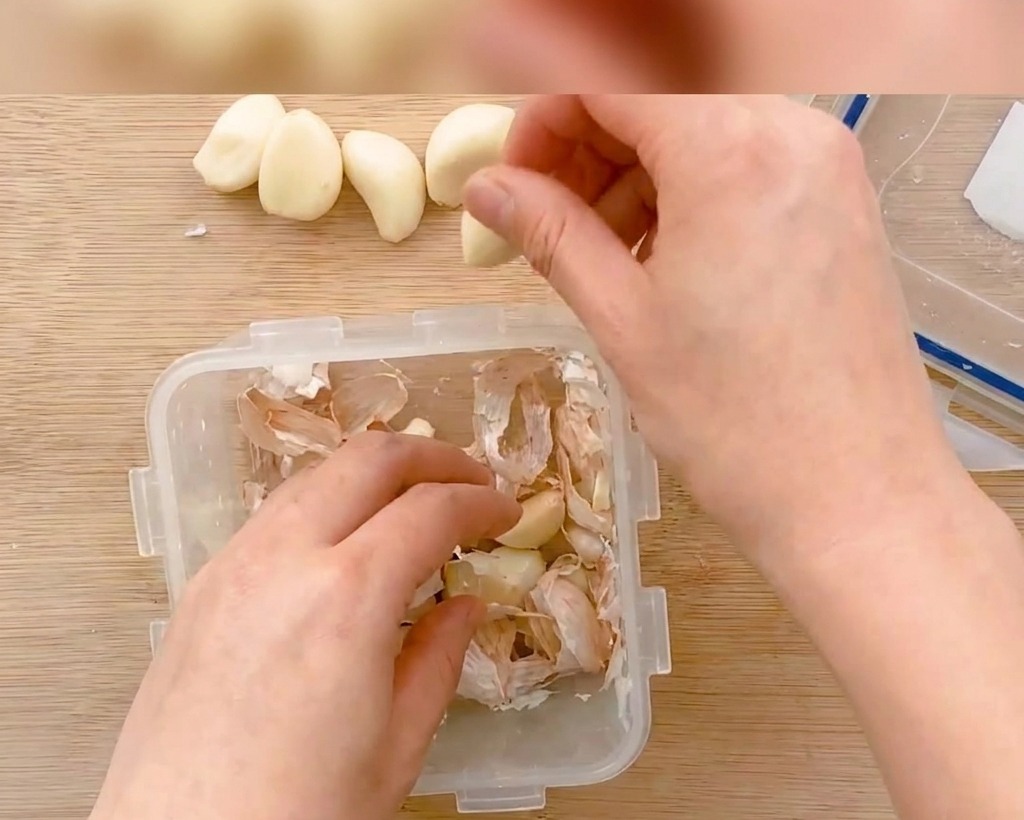 껍질을 깐 마늘을 도마 위에서 얇게 써는 모습.