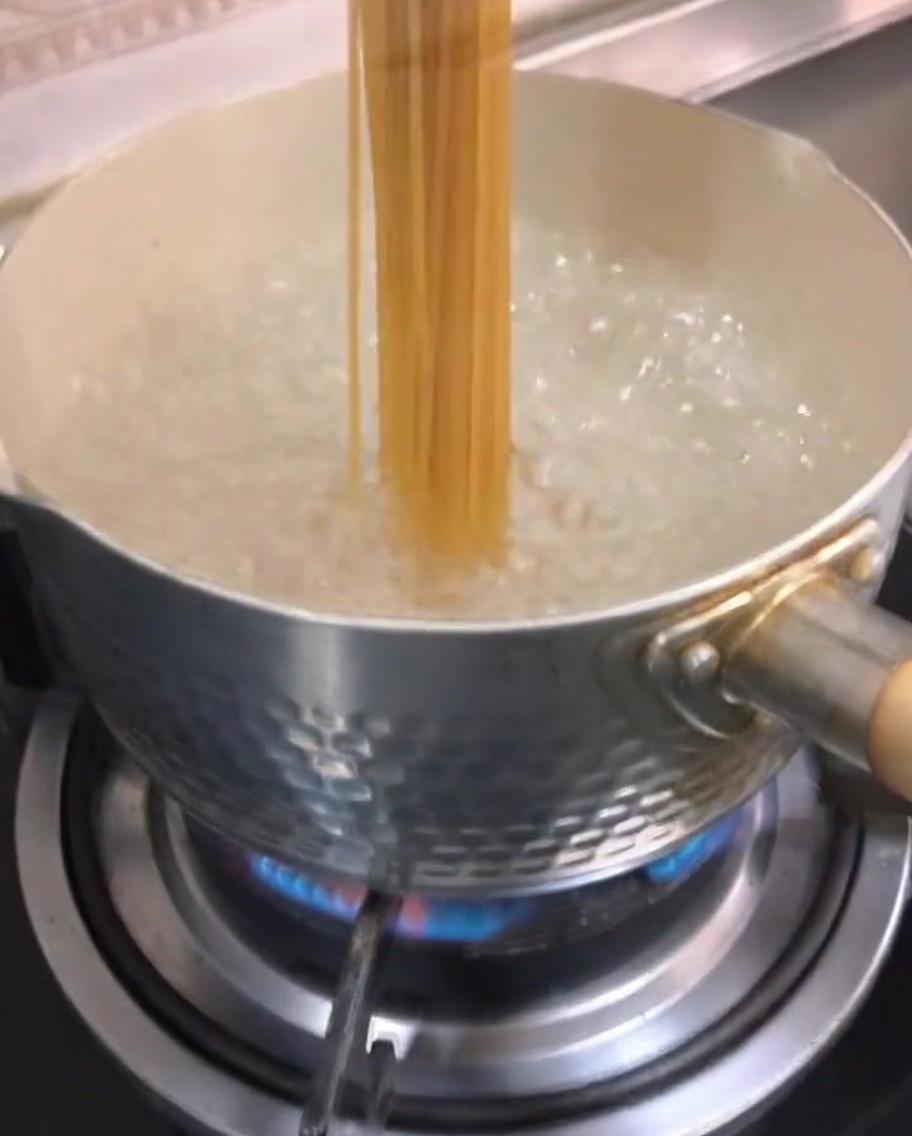 끓는 물이 담긴 냄비에 스파게티 면을 넣는 모습.