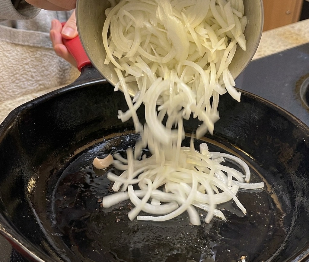 프라이팬에 채썬 양파를 넣고 볶는 모습.