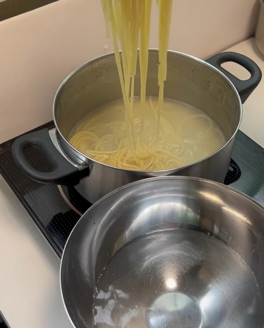 삶아진 스파게티 면을 찬물이 담긴 스테인리스 볼로 옮기는 모습.