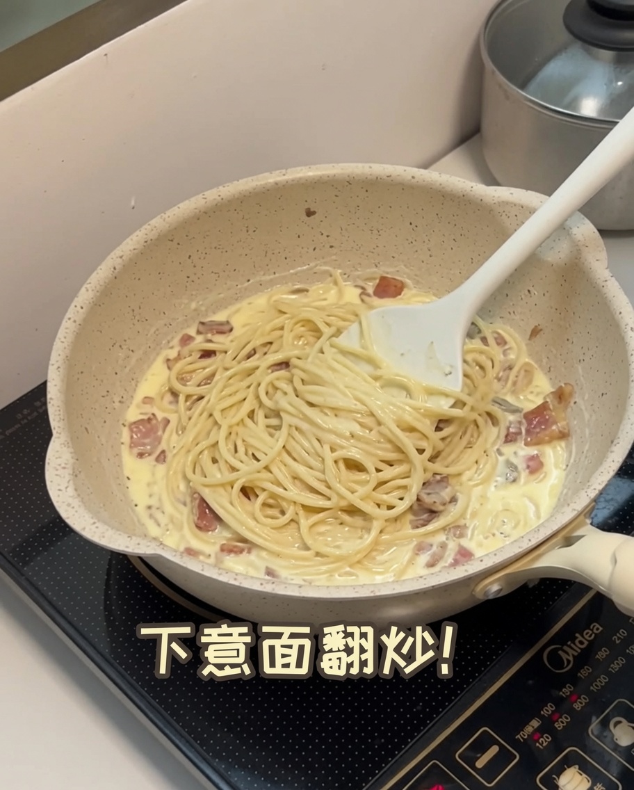 소스가 담긴 팬에 삶은 스파게티 면을 넣고 섞는 모습.