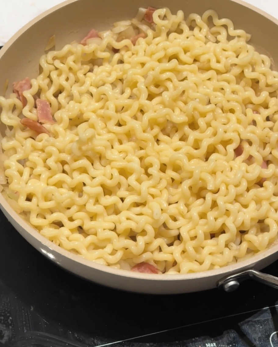 팬에 담긴 면 위로 저지방 우유를 붓는 모습.
