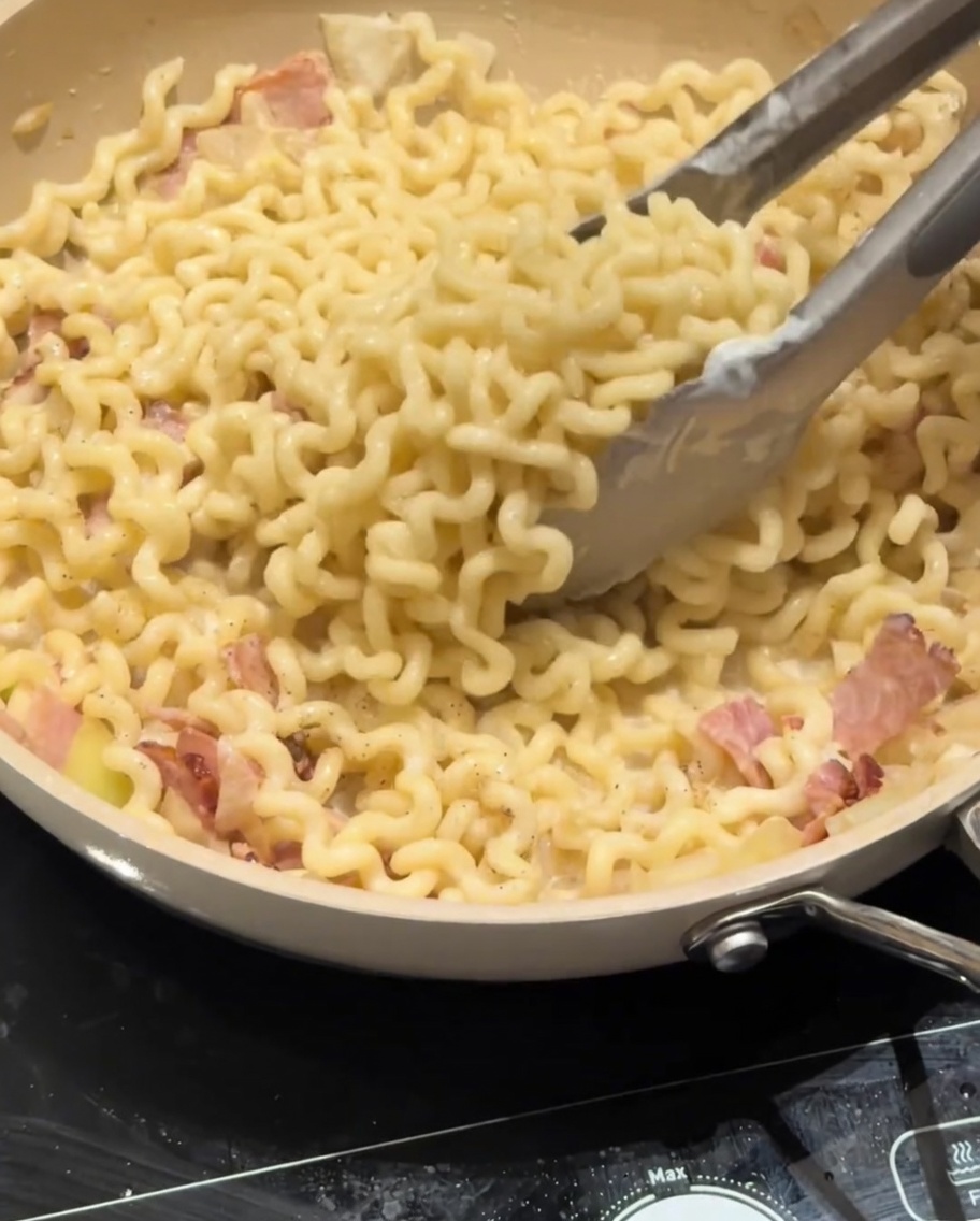 완성되어가는 파스타 위에 파마산 치즈를 뿌리는 모습.
